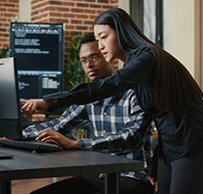 two software engineers review code on desktop monitor